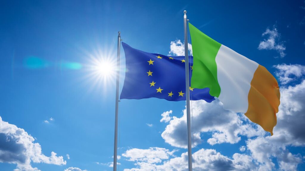 European Union and Irish flags waving under a sunny sky. NotaryPublic24 offers professional assistance with verifying and notarizing the UK ID1 Form for property transactions, including remote and apostille services.