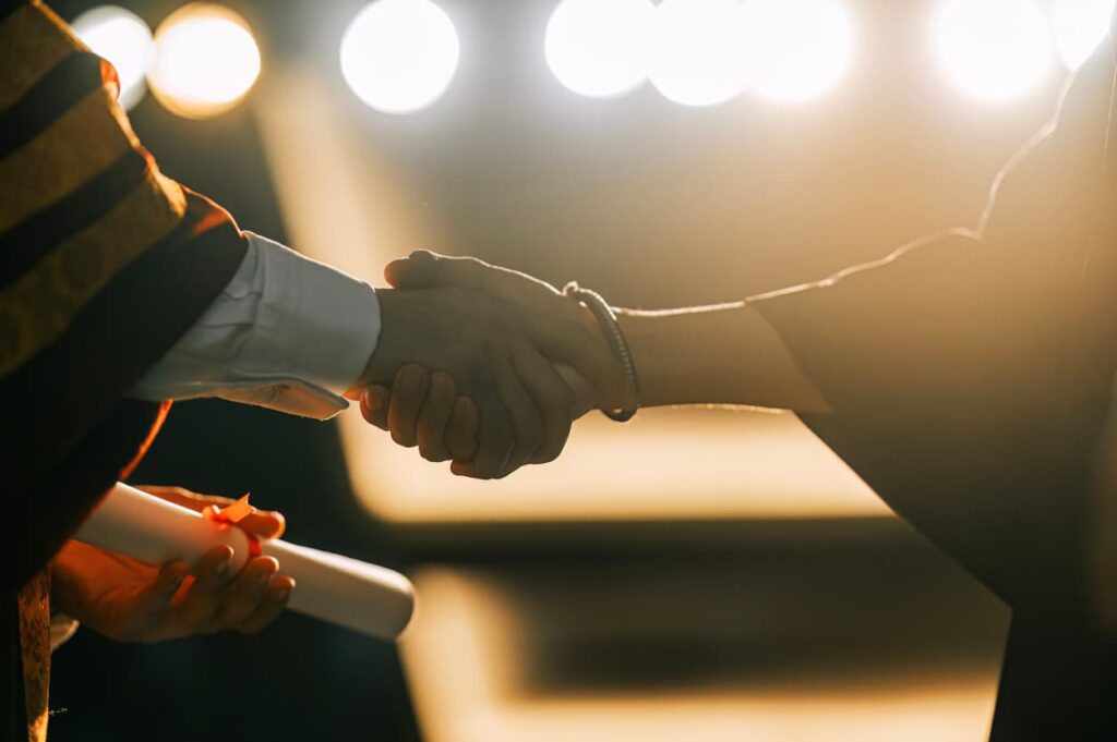 Handshake at graduation ceremony symbolizing international recognition of academic qualifications with Degree Certificate Apostille by NotaryPublic24 online notary services.